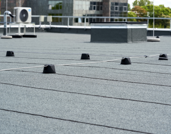 Commercial roofer applying silicone roof coating on a flat commercial roof in Commack, NY