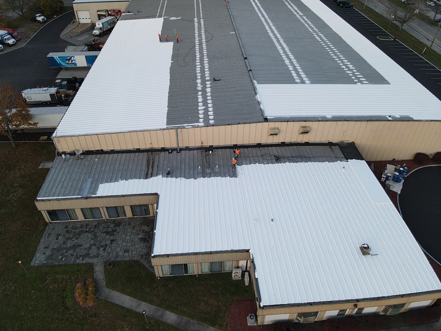 Top view of a large commercial metal roof in the process of getting a white liquid coating applied