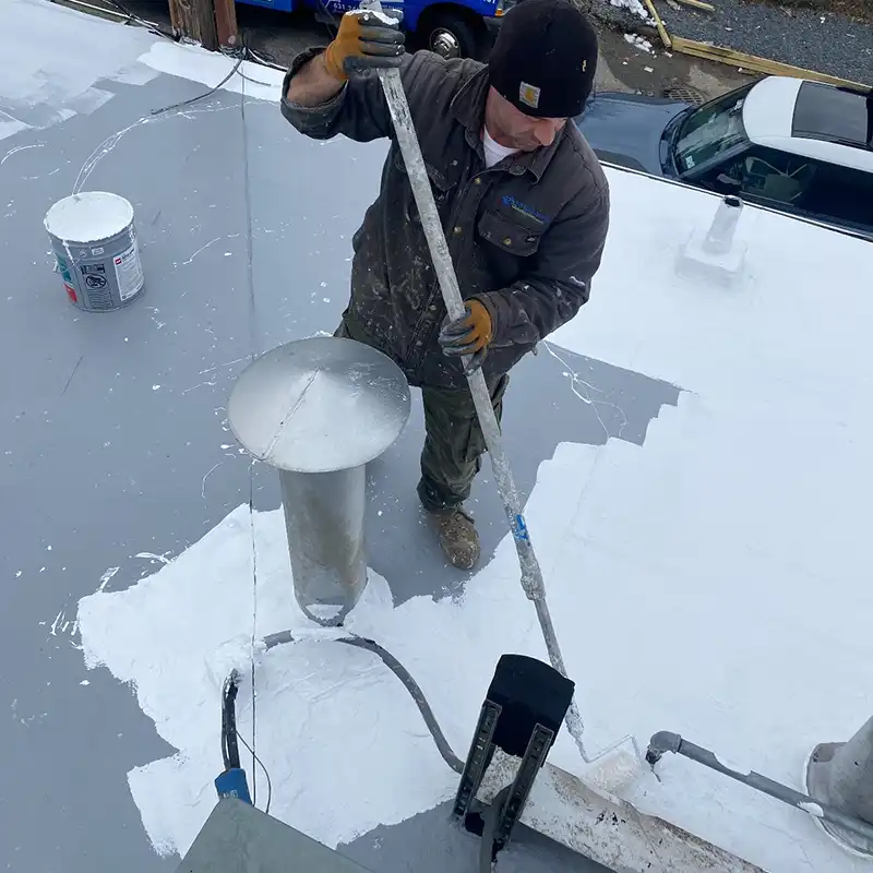 Worker applying coating on strip store roof