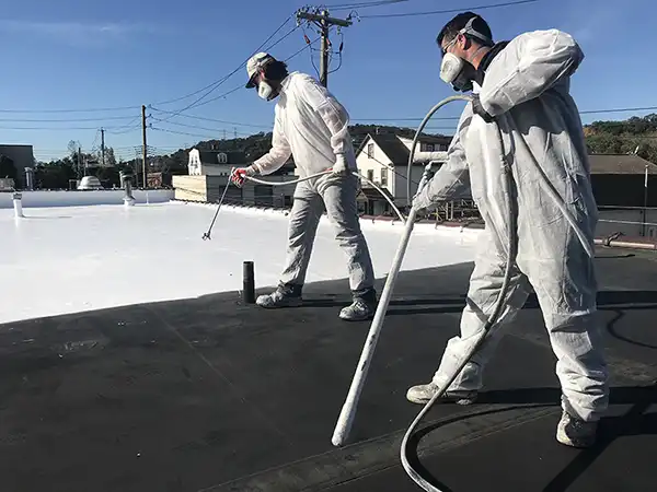 Workers applying roof coating on a commercial roof