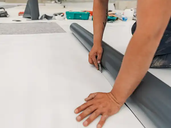 Close up of a worker cutting a piece off of a TPO sheet