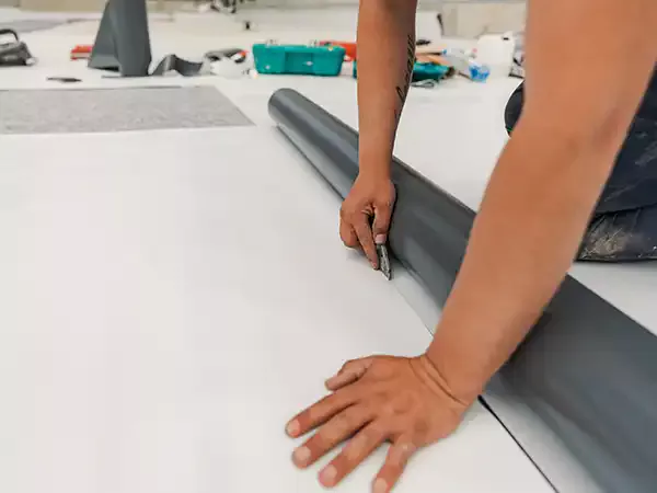 Close up of a worker cutting a piece off of a TPO sheet